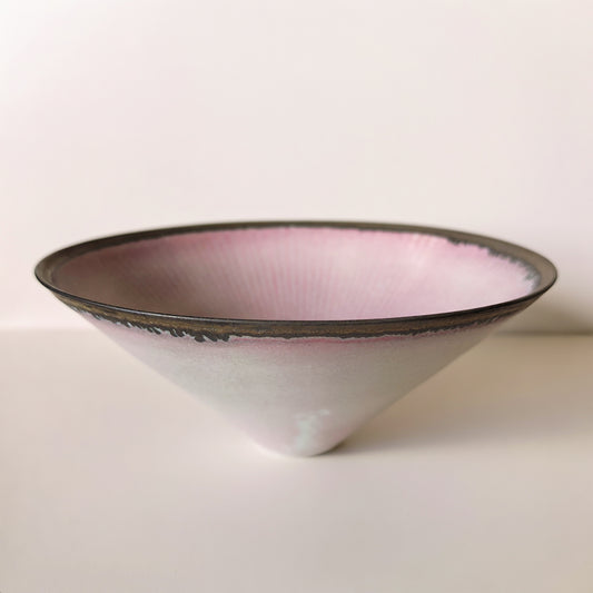 Wide conical bowl, white outside and soft pink within, edged by a thin dark speckled rim.