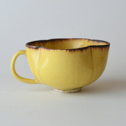 Bright yellow crackle-glazed cup with a petal-shaped rim edged in dark brown, and a small loop handle.