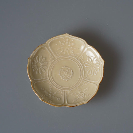 Flower-shaped cream plate moulded with a fine snowflake pattern across its face.