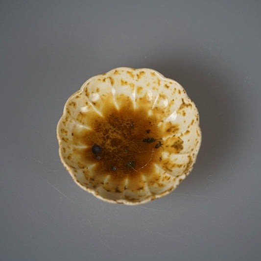 Small fluted plate with a scalloped rim, its pale yellow glaze pooling amber at the centre.