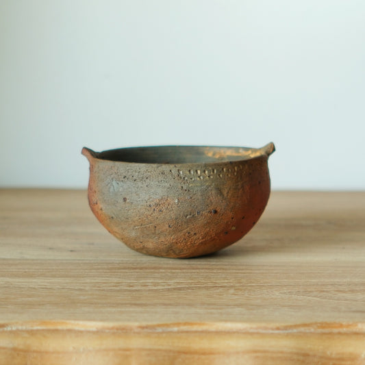 Two-handled bowl in mottled brown and grey wood-fired clay with two small rim lugs.
