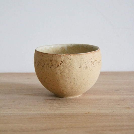 Deep cream tea bowl with a sandy speckled outside and a smooth pale glazed interior.