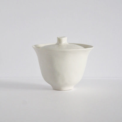 White porcelain lidded tea bowl with a flat lid and a small pointed knob.