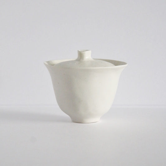 White porcelain lidded tea bowl with a flat lid and a small pointed knob.