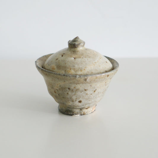 Small lidded bowl in chalky speckled cream with a pinched knob on its domed lid.