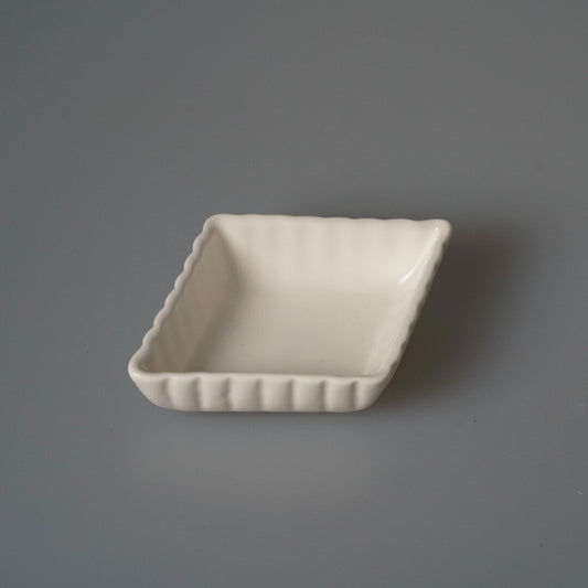 Small square white porcelain dish with fluted sides and softly rounded corners.