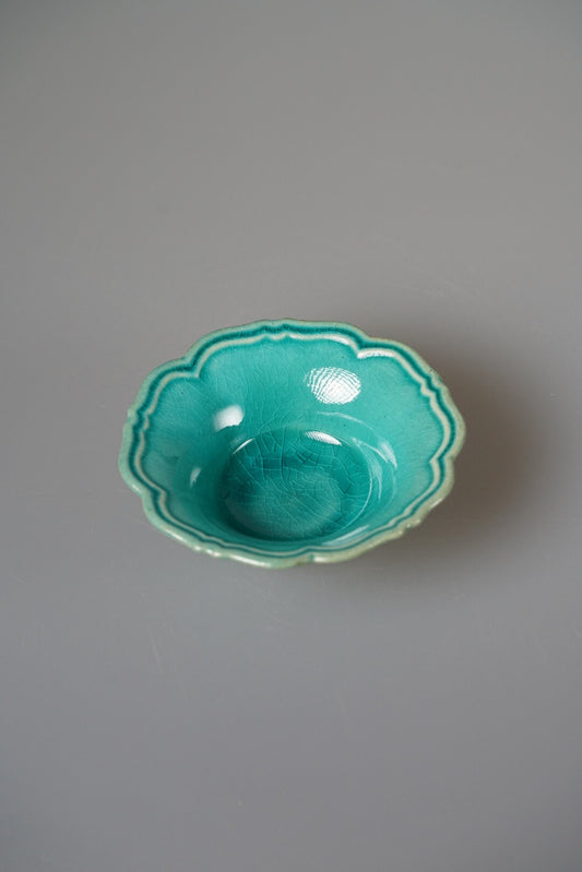 Small deep plate with a scalloped rim in bright turquoise green glaze.