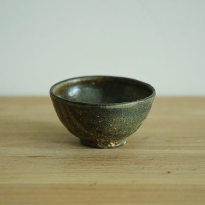 Footed rice bowl in deep olive wood-fired glaze with warm brown breaking through at the rim.