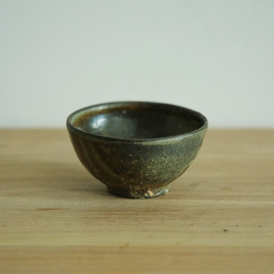 Footed rice bowl in deep olive wood-fired glaze with warm brown breaking through at the rim.