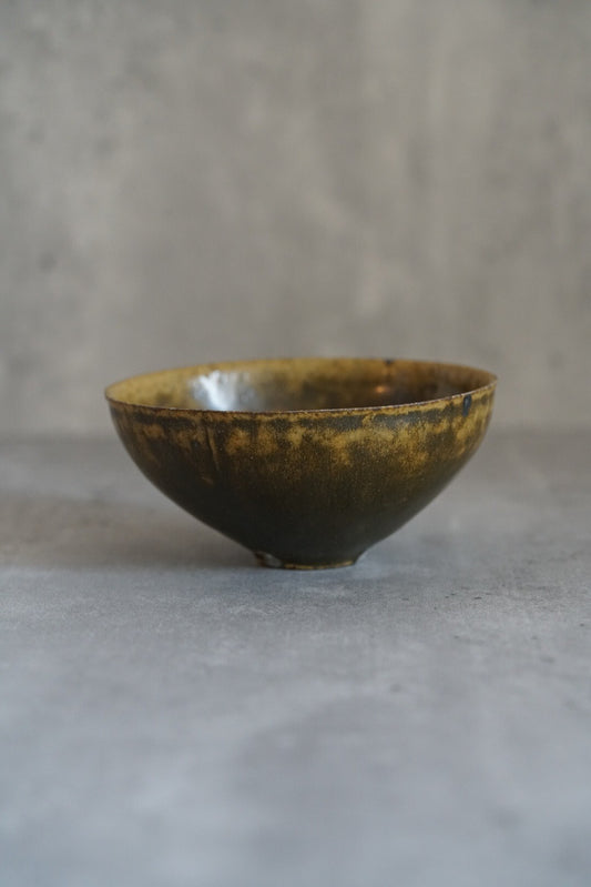 Small bowl in mottled olive and amber stone glaze, its rim thinning to a fine edge.