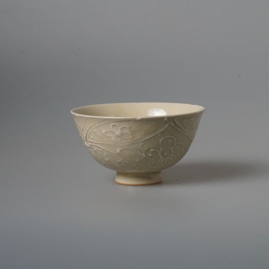 Footed bowl in soft grey-blue glaze, carved with faint flowers around its outer wall.