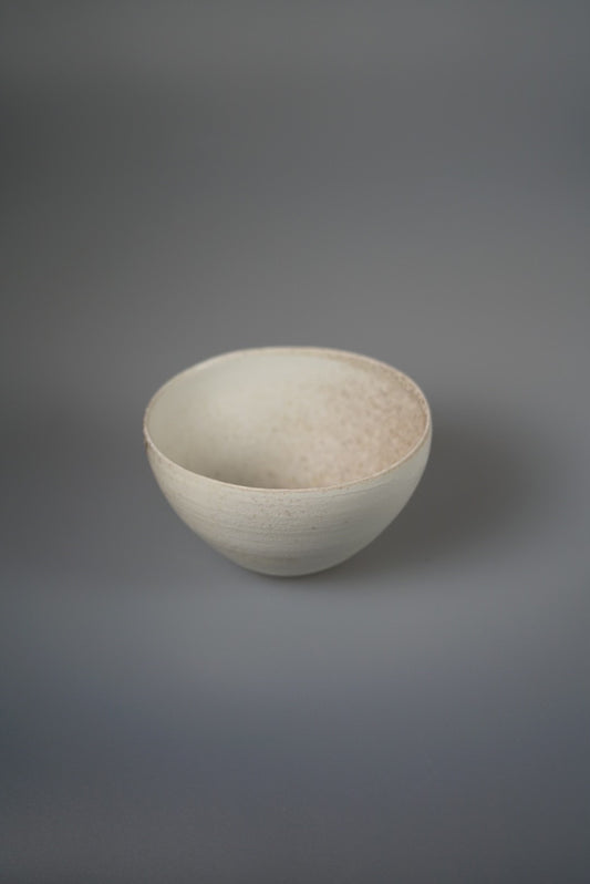 Deep white porcelain bowl with a softly speckled interior and a thin clean rim.