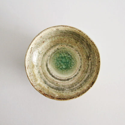 Small cream rice bowl seen from above with a bright jade green pool at its centre.