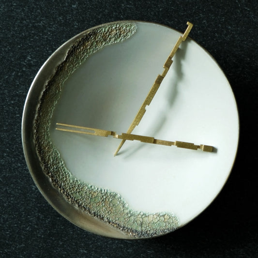 Two slim brass forks laid across a white and green dish like the hands of a clock.