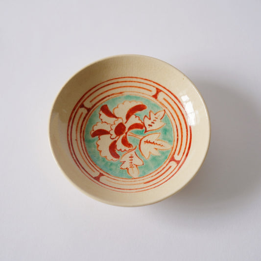 Small cream plate painted in red and green with a fine floral roundel and banded rings.