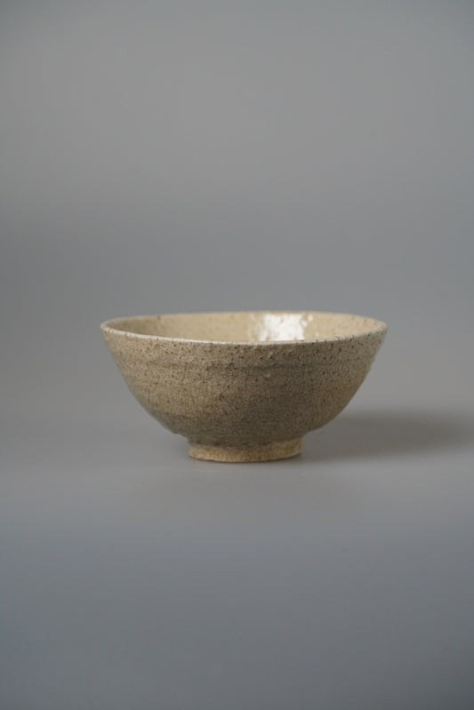 Footed bowl in speckled sandy cream with a smooth pale glazed interior.
