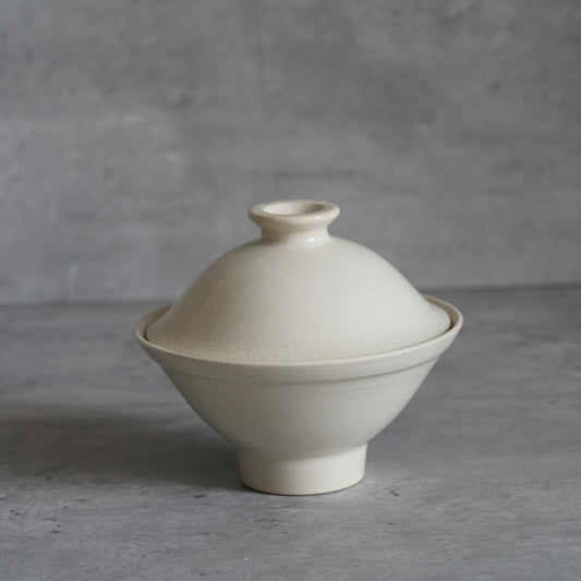 Cream lidded bowl on a low foot, its domed lid topped with a small knob.