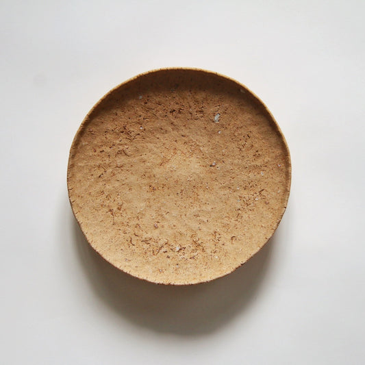 Round plate in sandy brown with a coarse, cork-like surface, lit against white.