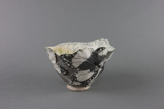 Tea bowl shaped like an opening flower calyx, its petals marbled in black and cream.