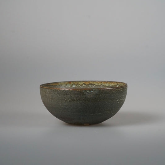 Wide shallow bowl in mottled olive green with a coarse ridged outer wall.