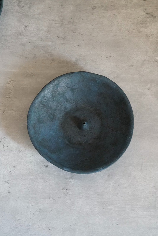 Round incense stand in deep blue-grey with a small central hole, seen from above.