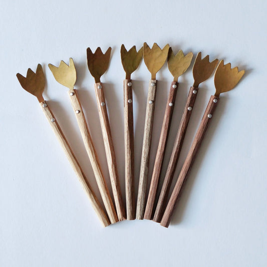Nine brass forks with tulip-shaped heads and wooden handles, fanned out on a pale blue ground.