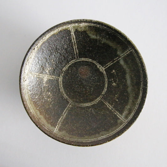 Round plate in dark olive glaze, divided into panels by pale lines radiating from the centre.