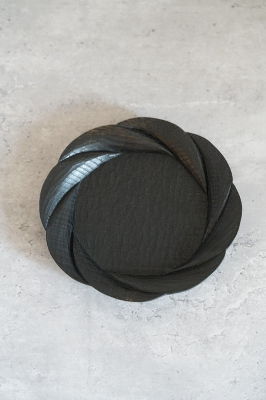 Round black lacquer tray with a swirling carved surface like overlapping petals.