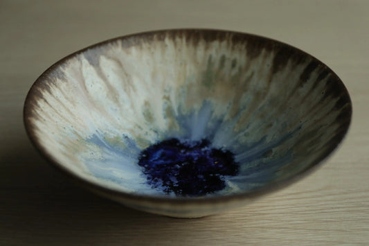 Shallow tea bowl with streaked cream and green glaze running to a deep blue pool at the centre.