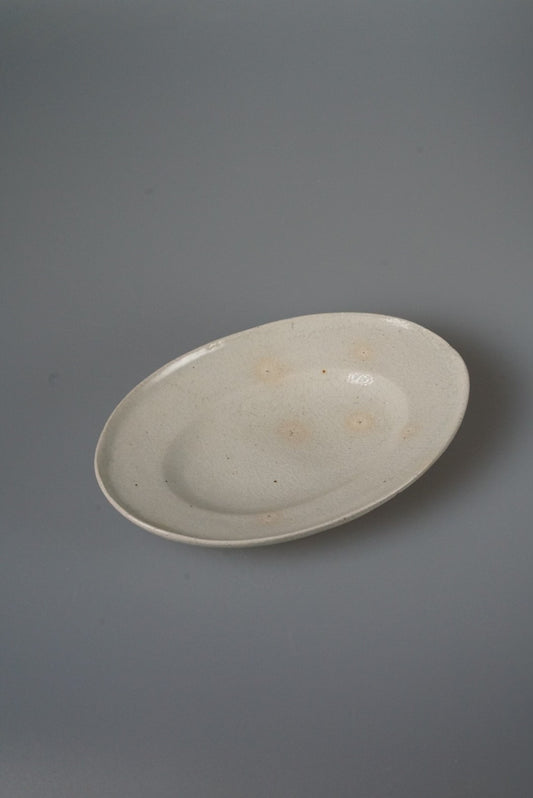 Oval plate in soft cream with a plain raised rim, lit against a pale grey ground.