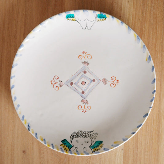 White plate painted with a fine diamond motif at the centre and small winged figures around the rim.