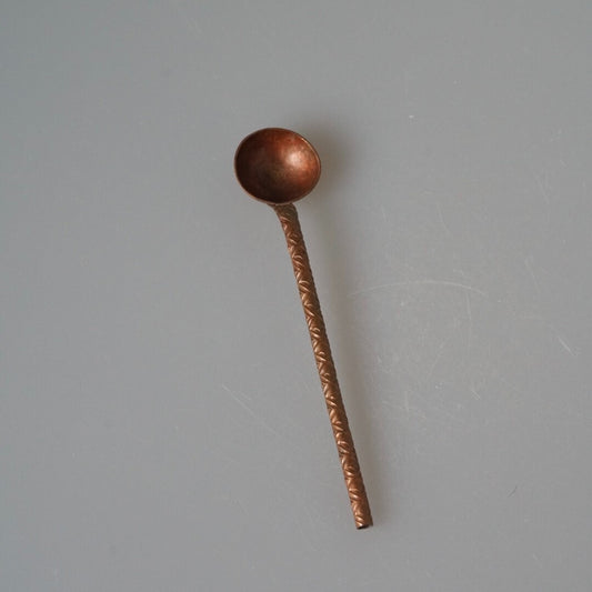 Slim copper coffee spoon with a round bowl and a hammered handle, in warm rose brown.