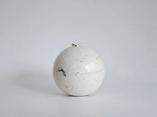 Round white slip-covered jar, almost spherical, its chalky surface flecked with dark grit.