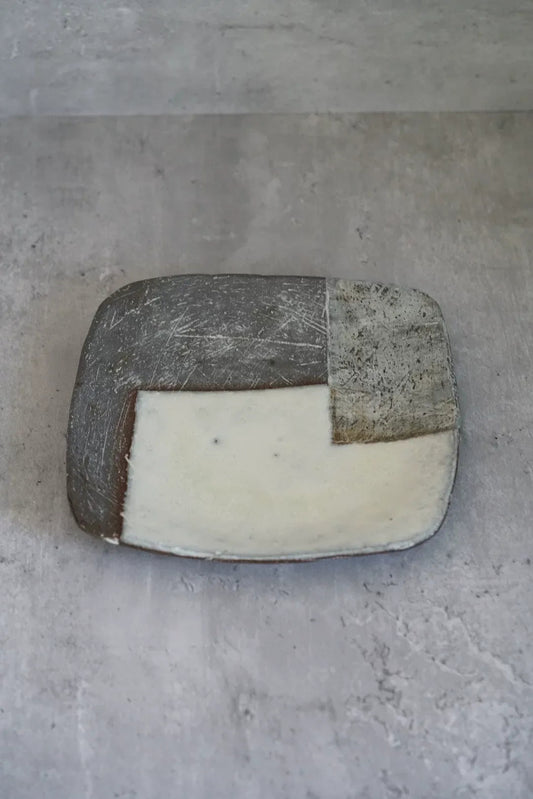 Square tray with rounded corners, its face divided into grey, white and brown blocks.