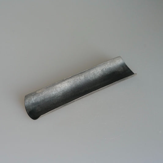Long narrow metal tea scoop with a rolled channel, finished in mottled pewter grey.