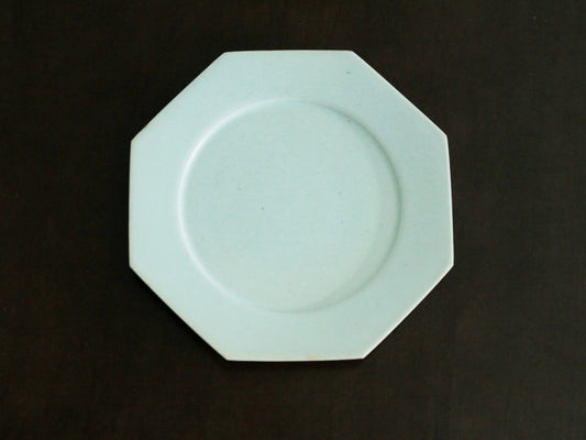 Octagonal white porcelain plate with a plain wide rim, lit softly against a dark ground.