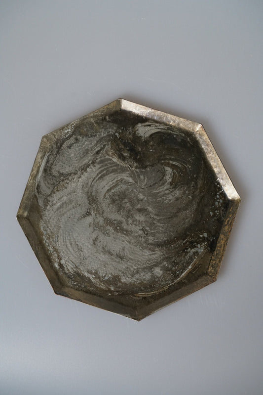 Octagonal metal tray with a swirled pewter surface and a bright brass edge.