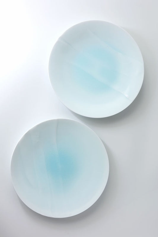 Two shallow bluish-white porcelain dishes with soft blue pooling in their centres.