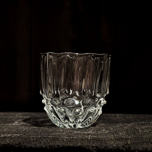 Round clear glass cup with a wavy rim, its base cut in a beaded honeycomb pattern.