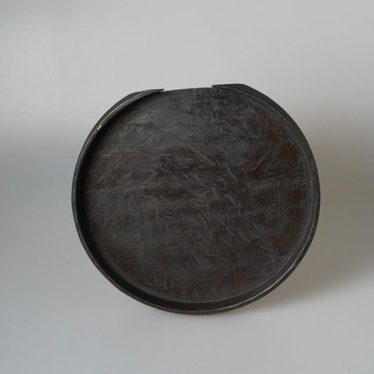 Round wooden tray with a raised rim, finished in dark lacquer over a carved surface.