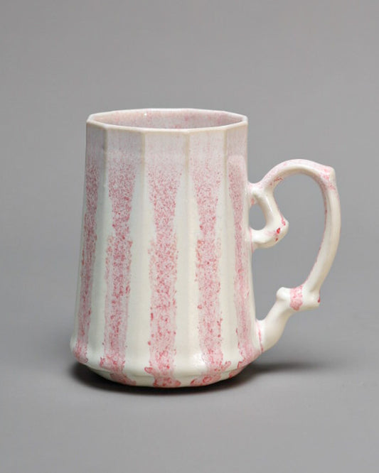 Tall cream porcelain mug with soft pink vertical streaks running down its ribbed sides and a curved handle.