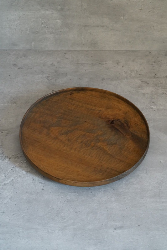 Round-cornered triangular wooden tray in warm honey brown, its grain sweeping across the face.
