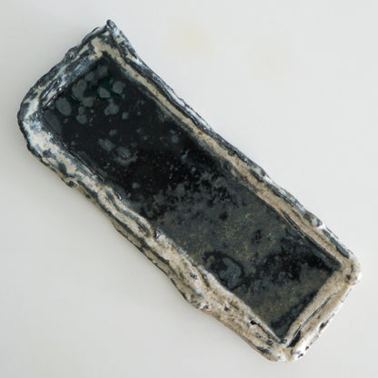 Long rectangular dish with a dark glazed well and rough torn cream edges.