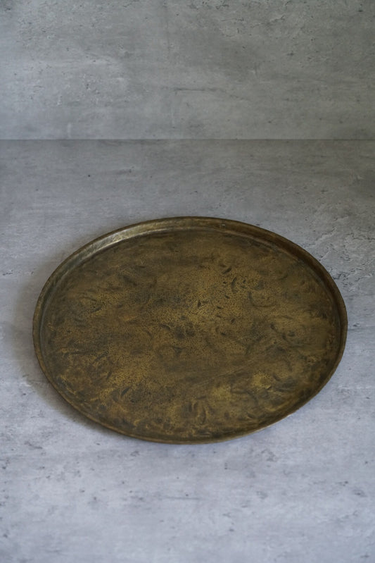 Large round copper tray with a raised rim and a richly mottled golden-brown surface.