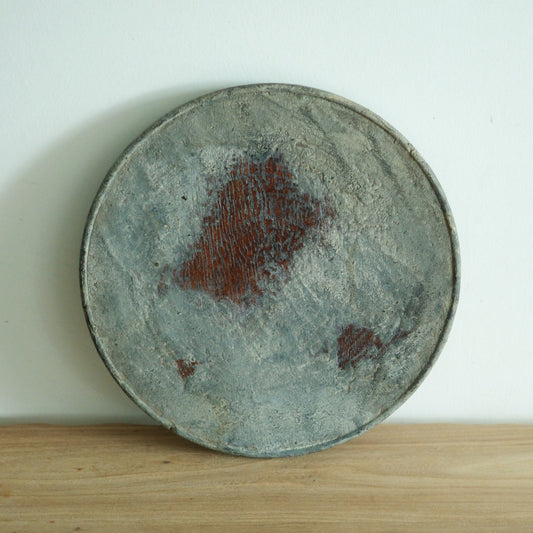 Large round tray in mottled grey lacquer with rust-red patches breaking through the surface.