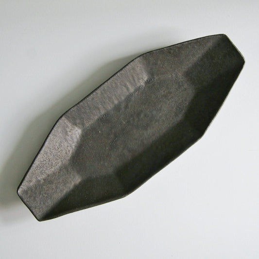 Long narrow faceted plate in matte iron brown, tapering to points at both ends.