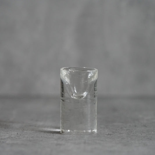 Small clear glass sake cup with a very thick base and softly dented sides.