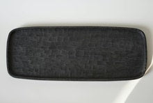Long rectangular black tray carved all over with a shallow basket-weave texture.