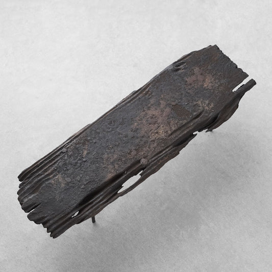 Long narrow board tray of scorched, split timber with a rough charred surface, on white.