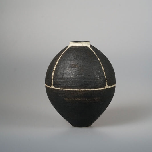 Broad black vase with a narrow neck, its dark surface divided by thin gold seams.